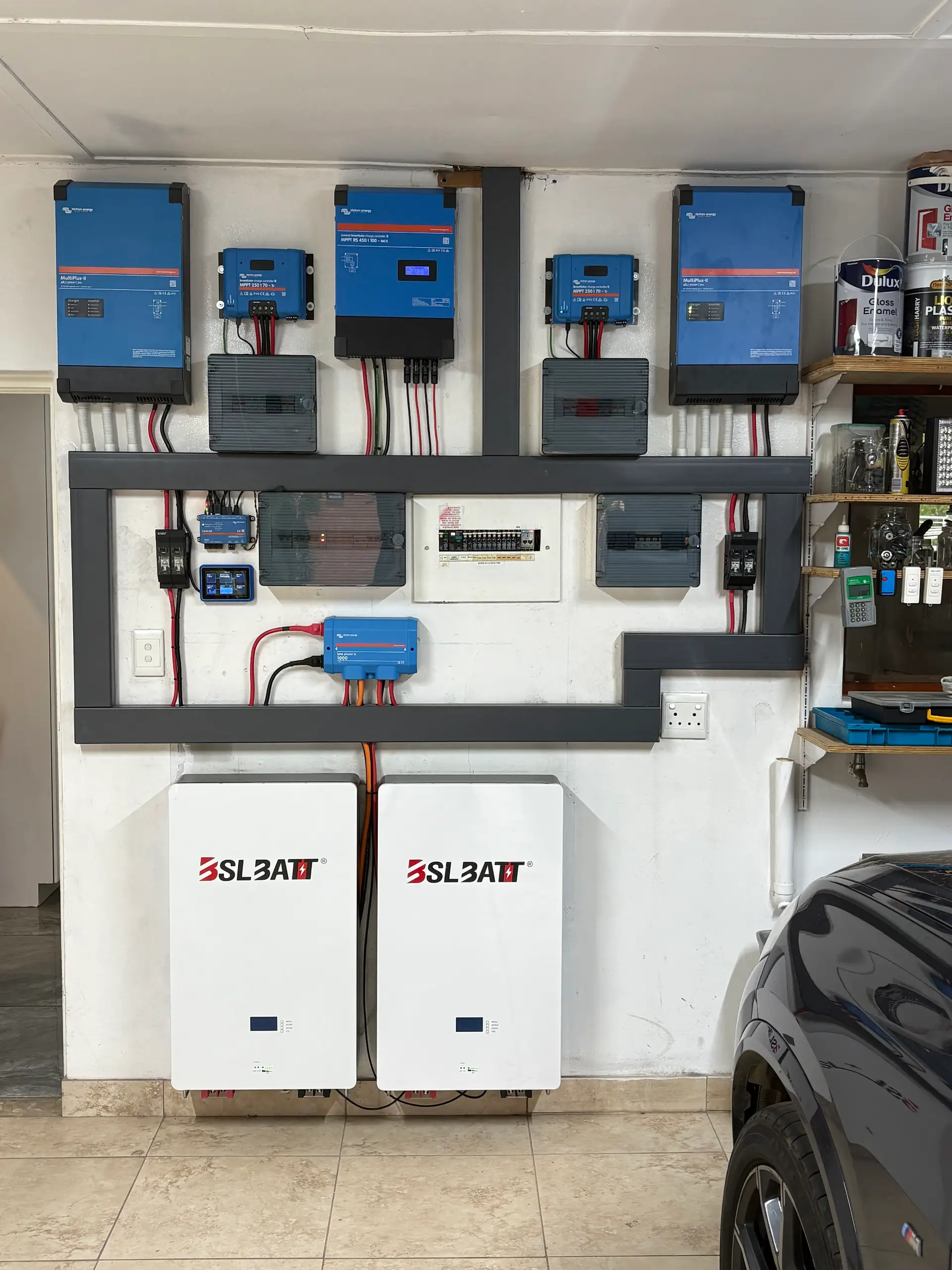 A finished Victron install: inverters, chargers and two batteries on a garage wall